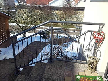 Schneebedeckter Garten mit Treppe und silbernem Metallgeländer im Vordergrund