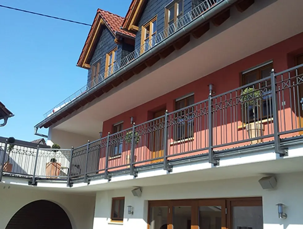 Mehrstöckiges Wohnhaus mit Balkon und Geländer unter blauem Himmel