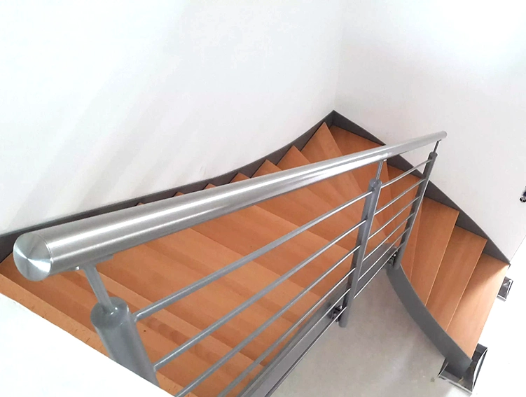Blick von oben auf eine gewendelte Treppe mit Holzstufen und einem silbernen Metallgeländer
