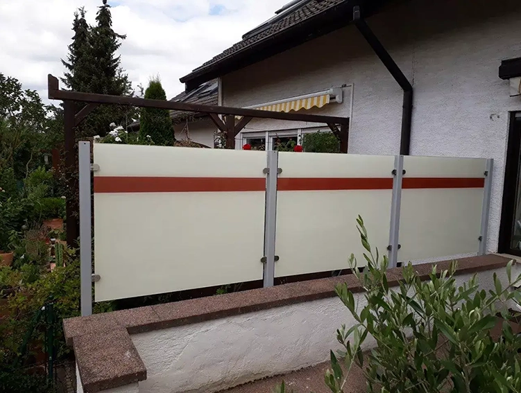 Haus mit weißer Fassade und braunem Zaun mit blickdichten Sichtschutzplatten und orangem Streifen