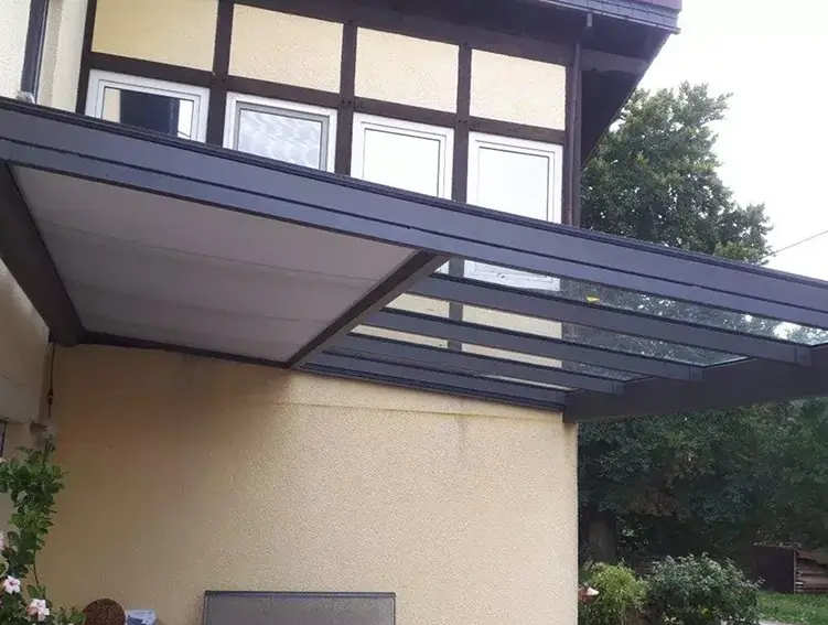 Terrasse mit Tisch, Stühlen und einem Hund unter dem Tisch neben einem Haus mit gelber Fassade und weißen Fenstern