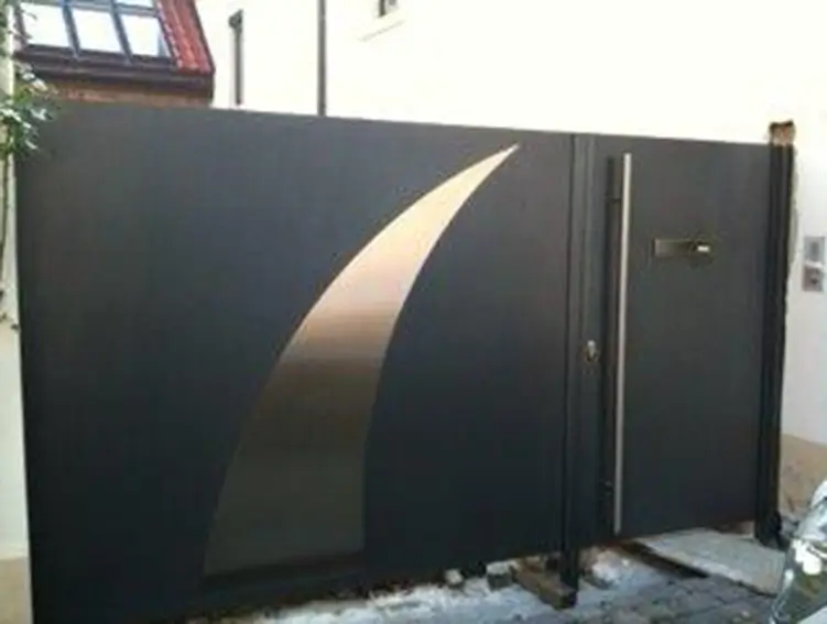 Schwarze Metalltore mit gebogenem, hell reflektierendem Streifen und integriertem Türflügel in einer Hauswand