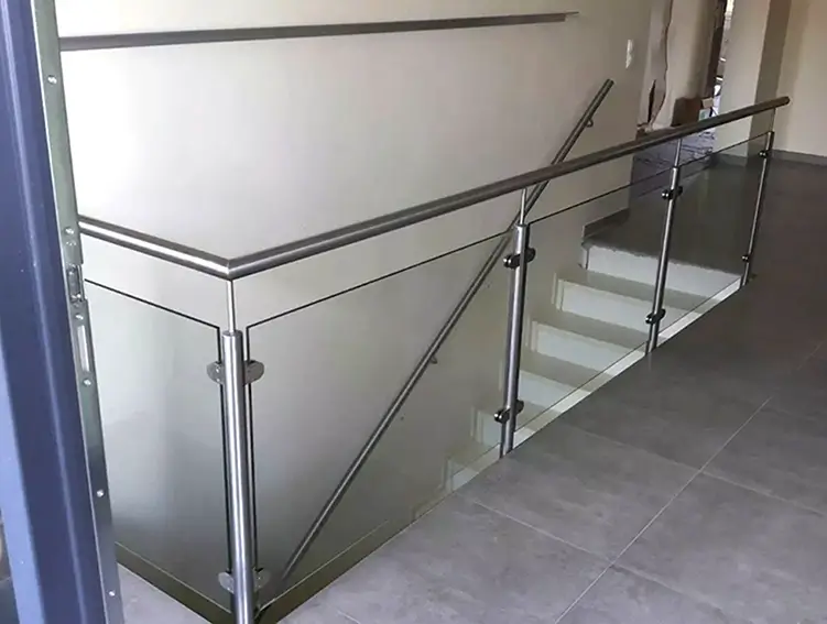 Treppengeländer aus Edelstahl mit Glasfüllung an einer hellen Treppe in einem Innenraum