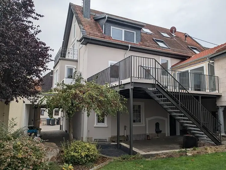 Mehrstöckiges Wohnhaus mit Außenbalkon und Treppe im Gartenbereich