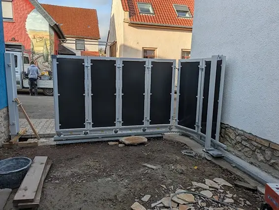 Halbhohe graue Betonfertigteile als Sichtschutzwand in einer kleinen Hofecke zwischen zwei Häusern