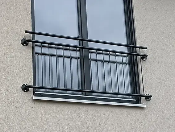 Fenster mit schwarzem Metallgeländer an einer hellen Fassade